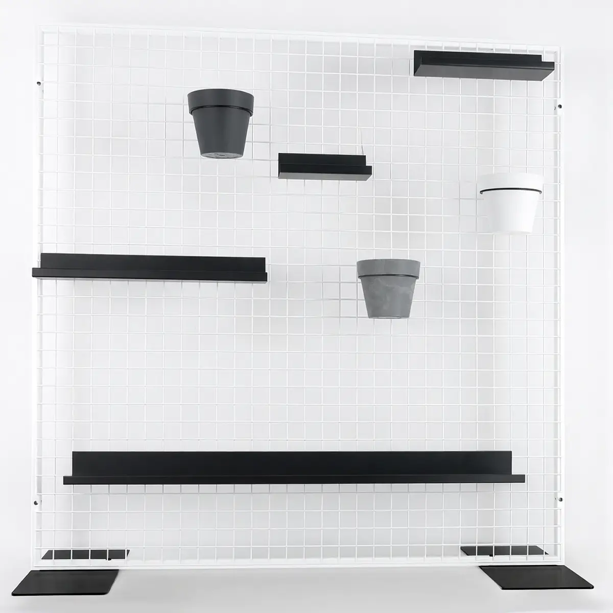 Wit metalen wandrooster met planken en bloempotten &ndash; voorbeeld van een modulair presentatiesysteem met accessoires.