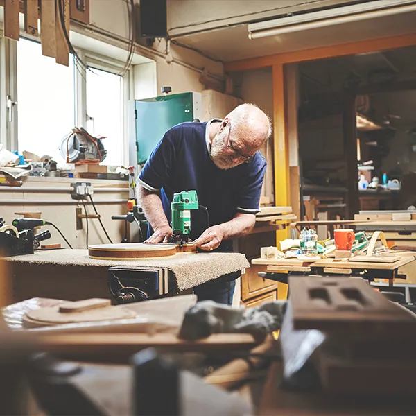 Vakman in een timmerwerkplaats tijdens het vervaardigen van houten elementen voor de garage-inrichting.